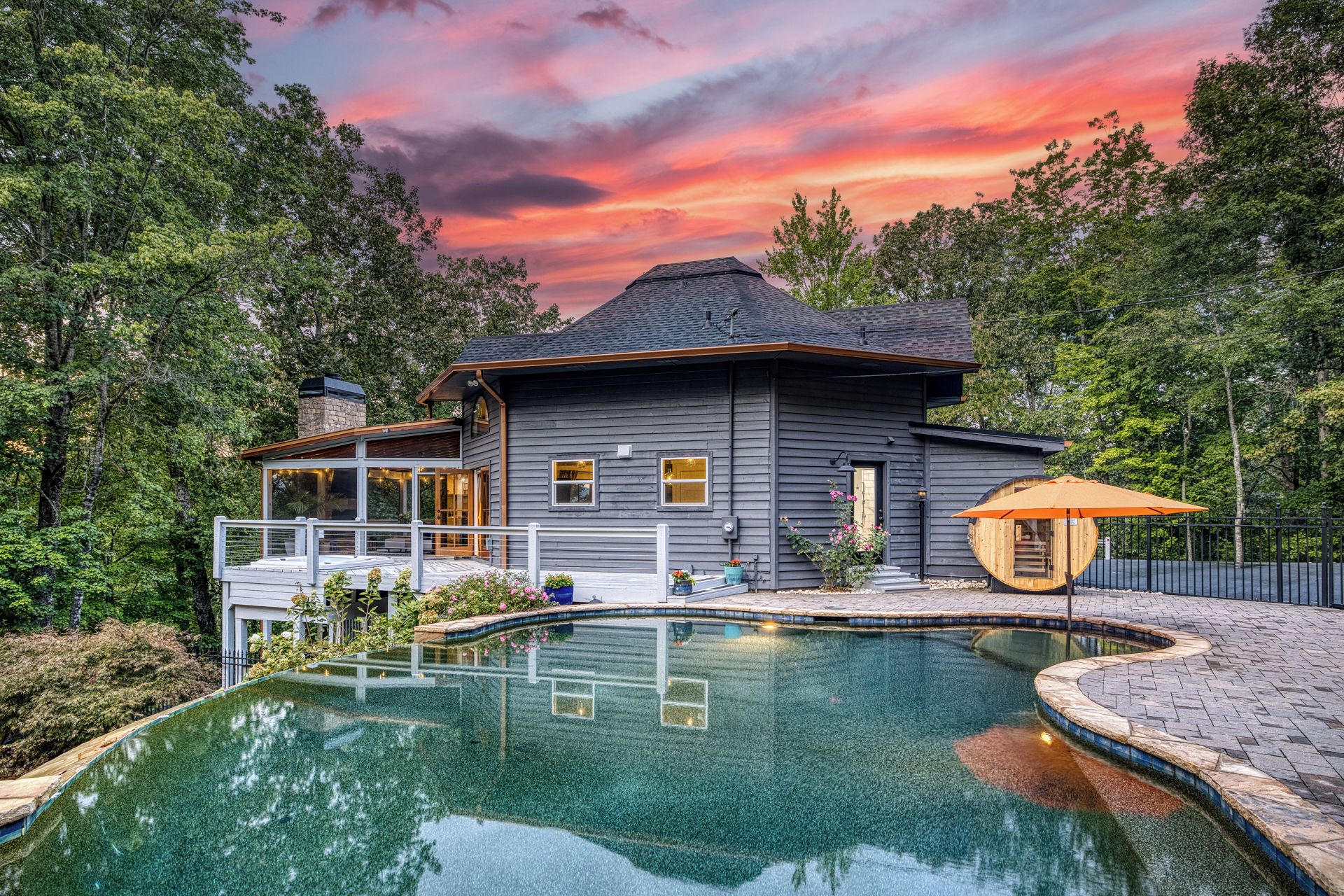 A two-story house with a swimming pool, surrounded by trees.