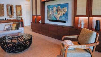A modern living room with a sofa, a chair, a coffee table, and a wall-mounted shelf with decorative items.