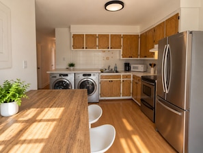 A modern kitchen with stainless steel appliances, wooden cabinets, and a central island with seating. - Vintage 2 chambres • Calme • Près métro (Montréal)