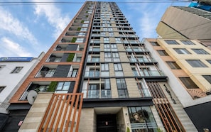 Un immeuble à plusieurs étages doté d’une architecture moderne, avec des balcons, de grandes fenêtres et une entrée bien visible.