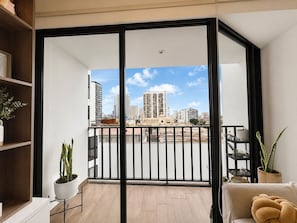 Un balcon avec vue sur la ville, un canapé et une plante en pot.