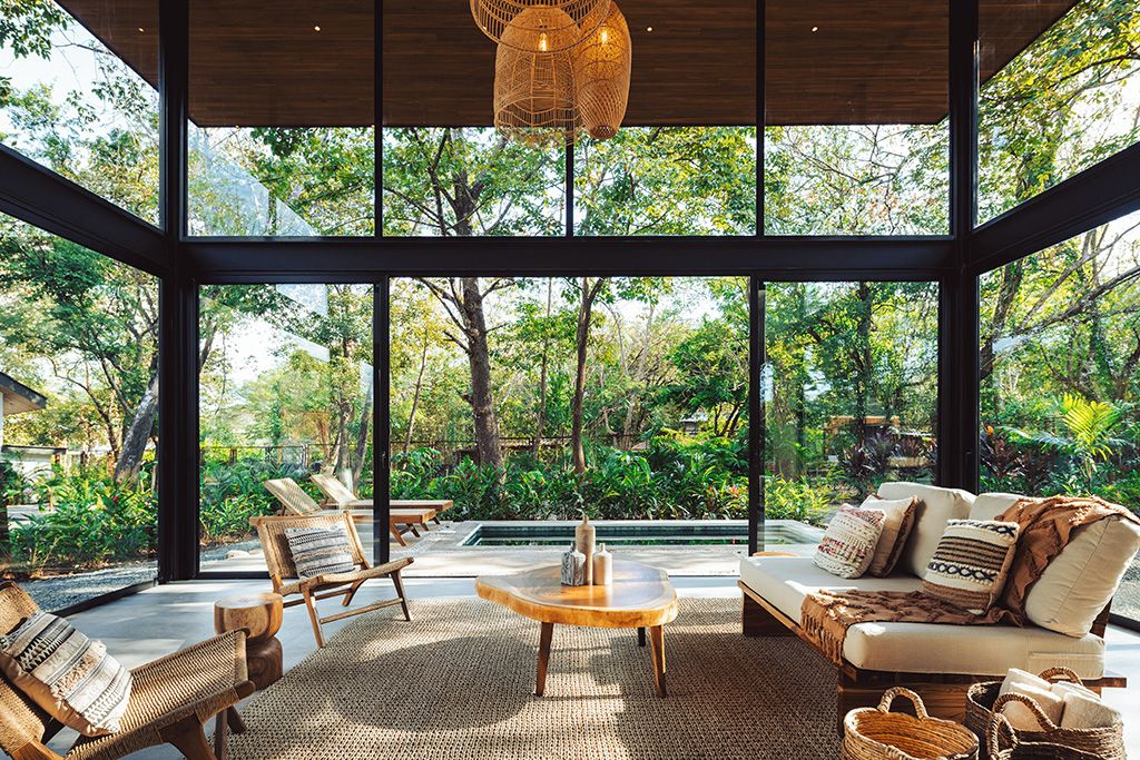 A spacious room with large windows, a wooden ceiling, and a central table with chairs.