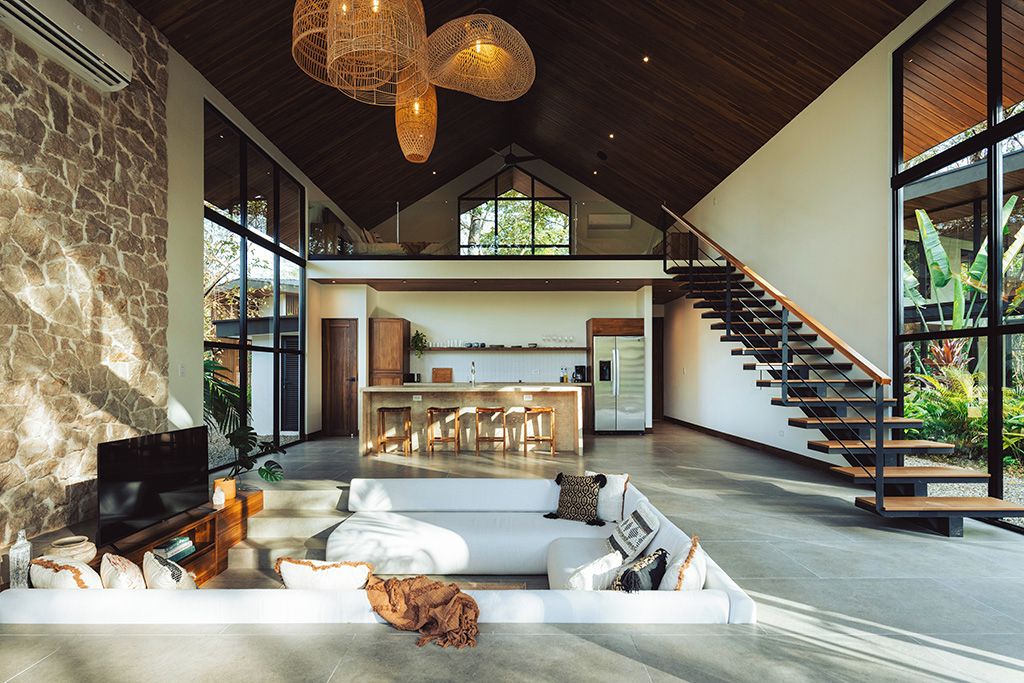 A spacious living area with a stone wall, a large flat-screen TV, and a white sofa.