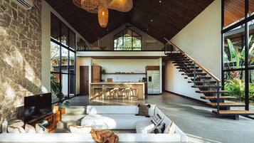 A spacious living area with a stone wall, a large flat-screen TV, and a white sofa.