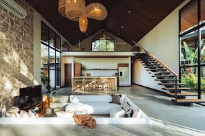 A spacious living area with a stone wall, a large flat-screen TV, and a white sofa.