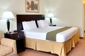 A hotel room with a bed, two bedside tables, a chair, and a framed picture on the wall.
