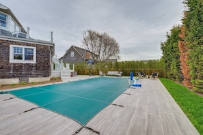 Un cortile con piscina, un pontile in legno e una casa con tetto spiovente.