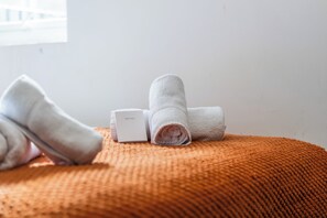 A neatly folded white towel and a white box labeled 'SLEEP WELL' on an orange textured ottoman. - Sutherland Apartments - Apt 28 (London)