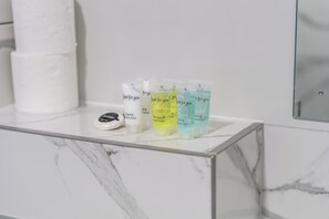 A bathroom shelf with toiletries including hand and body lotion, shampoo and conditioner, and bath and shower gel. - Sutherland Apartments - Apt 28 (London)