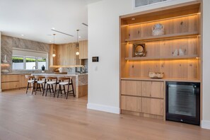 Een moderne keuken met houten kasten, een inbouwuilandschappen met barstoelen en een roestvrijstalen koelkast.
