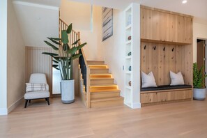 A modern interior with a wooden staircase, a seating area with cushions, and a large potted plant. - Gaviota Pavilion By Alora Reserve (Los Angeles)