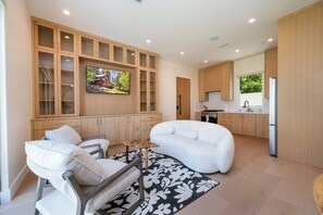 Een moderne woonkamer met een bank, fauteuil en een televisie bevestigd aan een houten wand.