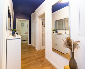 Un pasillo con suelo de madera que conduce a un dormitorio y un baño.