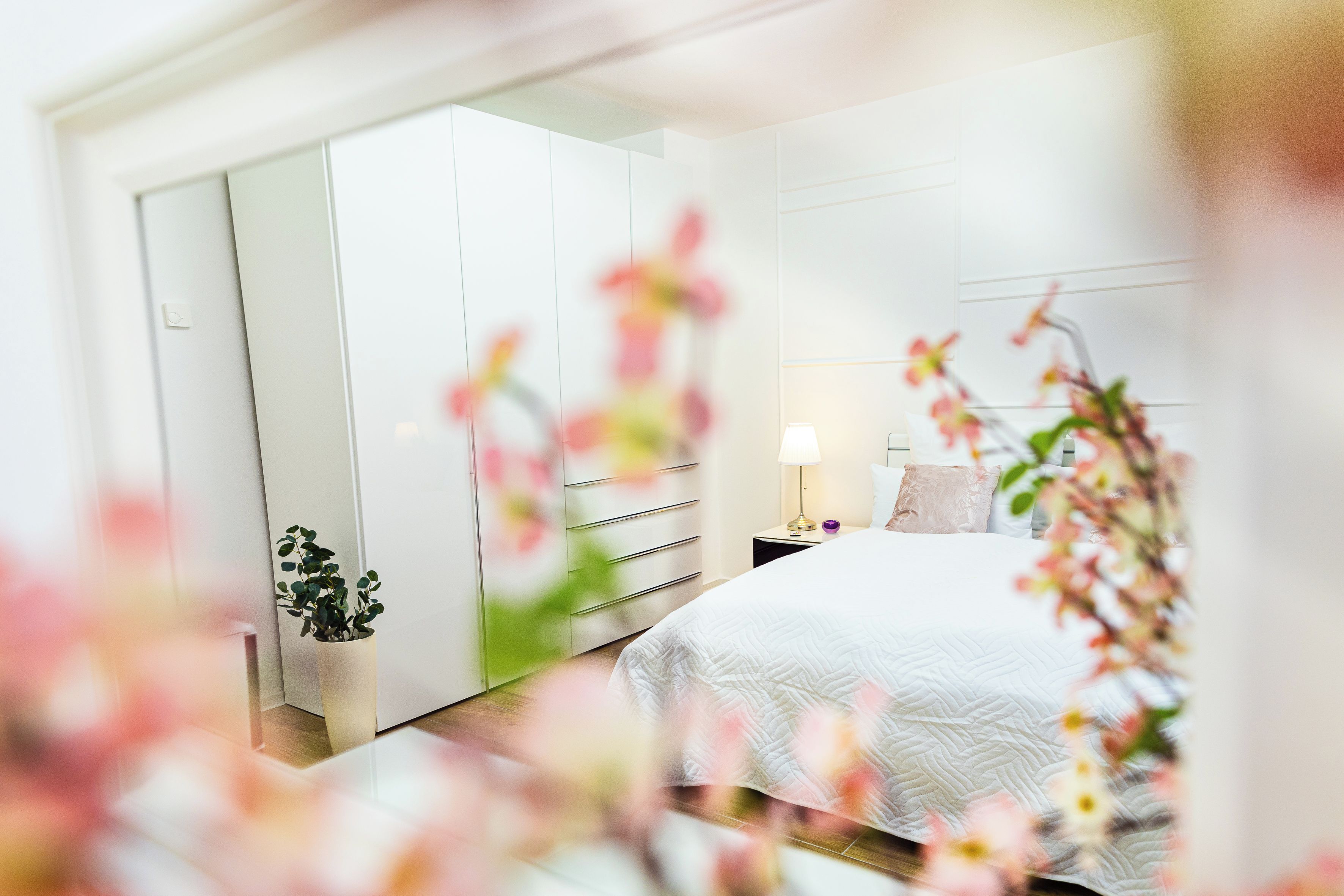 Une chambre à coucher avec un lit, une table de chevet, une lampe et une plante en pot.