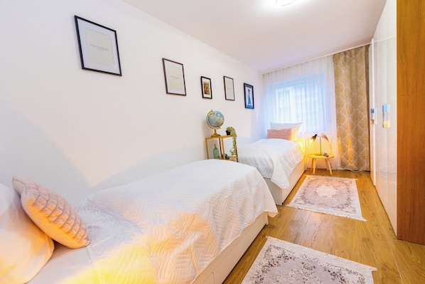 Una habitación de hotel con dos camas, un globo terráqueo, una lámpara y fotografías enmarcadas en la pared.