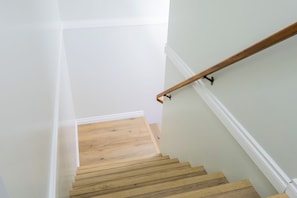 Una escalera con escalones de madera y paredes blancas.