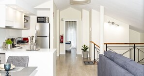 Eine moderne Küche mit Mikrowelle und Kühlschrank, ein Essbereich mit Tisch und Stühlen, ein Wohnzimmer mit Sofa und eine Treppe zu einer weiteren Ebene.
