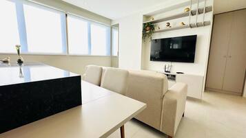 Una sala de estar moderna con un sofá, una mesa de comedor y un televisor montado en la pared.