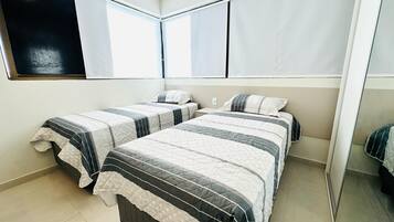 A bedroom with two beds, a large window, and a mirror.