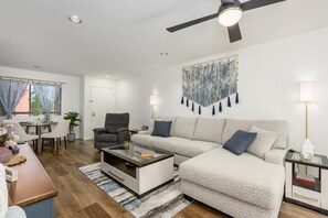 A modern living room with a sofa, armchair, coffee table, and a ceiling fan. - CASA AERIE- Amazing Pool View 3rd floor (Phoenix)