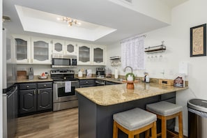 Granite countertops extend over the breakfast bar with two cushioned stools beneath a recessed ceiling light. - CASA AERIE- Amazing Pool View 3rd floor (Phoenix)