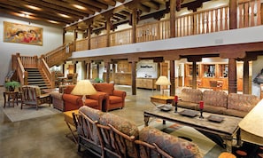 A spacious lobby with a high ceiling, wooden beams, a staircase, and a dining area. - Tasteful apartment, 2 bedrooms, cosy,warm, inviting (Taos)