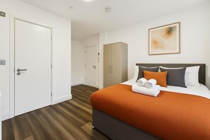 A hotel room with a bed, a wardrobe, a mirror, and a painting on the wall. - Sutherland Apartments - Apt 29 (London)