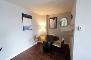 A dining area with a round table, four chairs, a wall-mounted lamp, and two framed artworks. - Cozy 2BR : Forest Park • WashU • Delmar Loop (St. Louis)