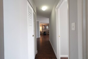 A hallway with white walls and wooden flooring leading to a dining area with a table and chairs. - Cozy 2BR : Forest Park • WashU • Delmar Loop (St. Louis)