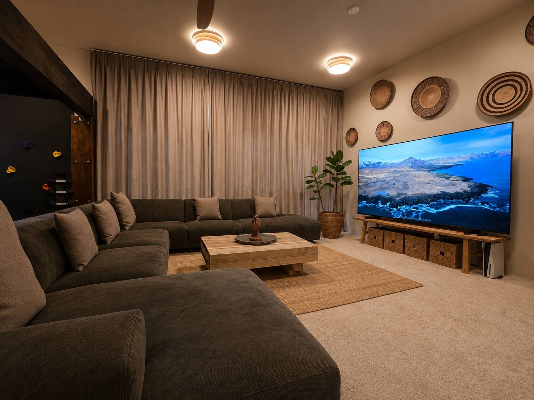 Una sala de estar moderna con un sofá modular, una mesa de centro, un televisor de pantalla plana grande y una pared de escalar.