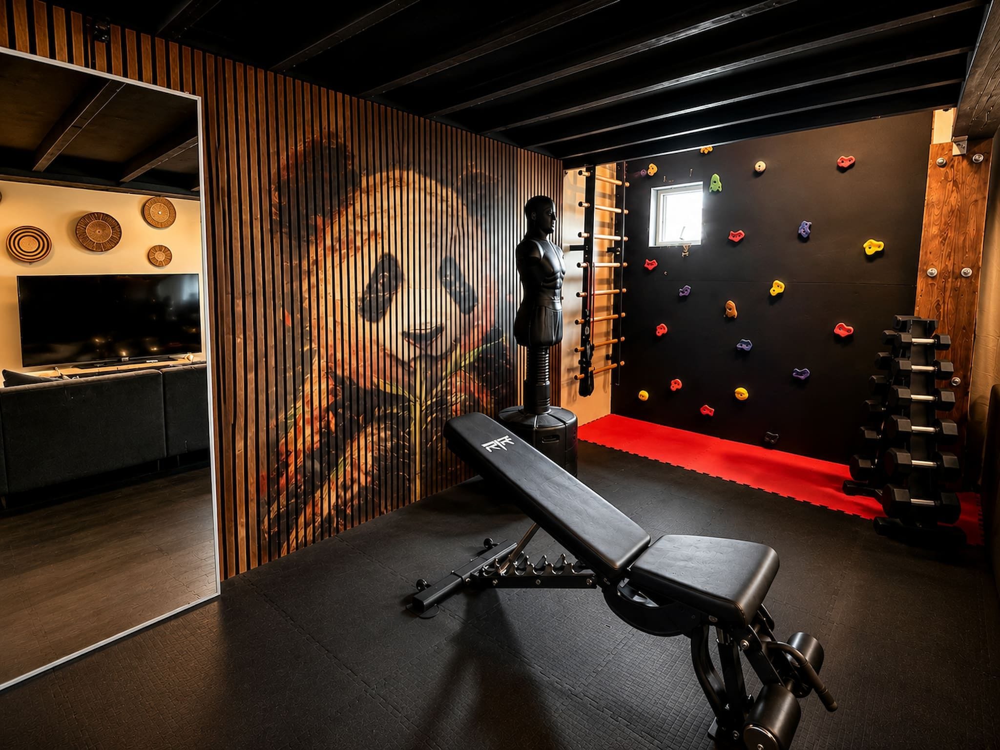 Un gimnasio con una pared de escalar, un banco y una barra con mancuernas.