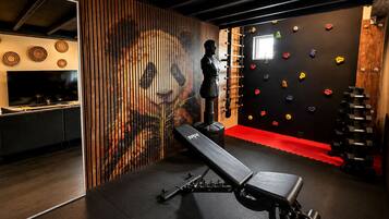 Un gimnasio con una pared de escalar, un banco y una barra con mancuernas.