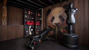 Un gimnasio con una banca, pesas y un saco de boxeo.