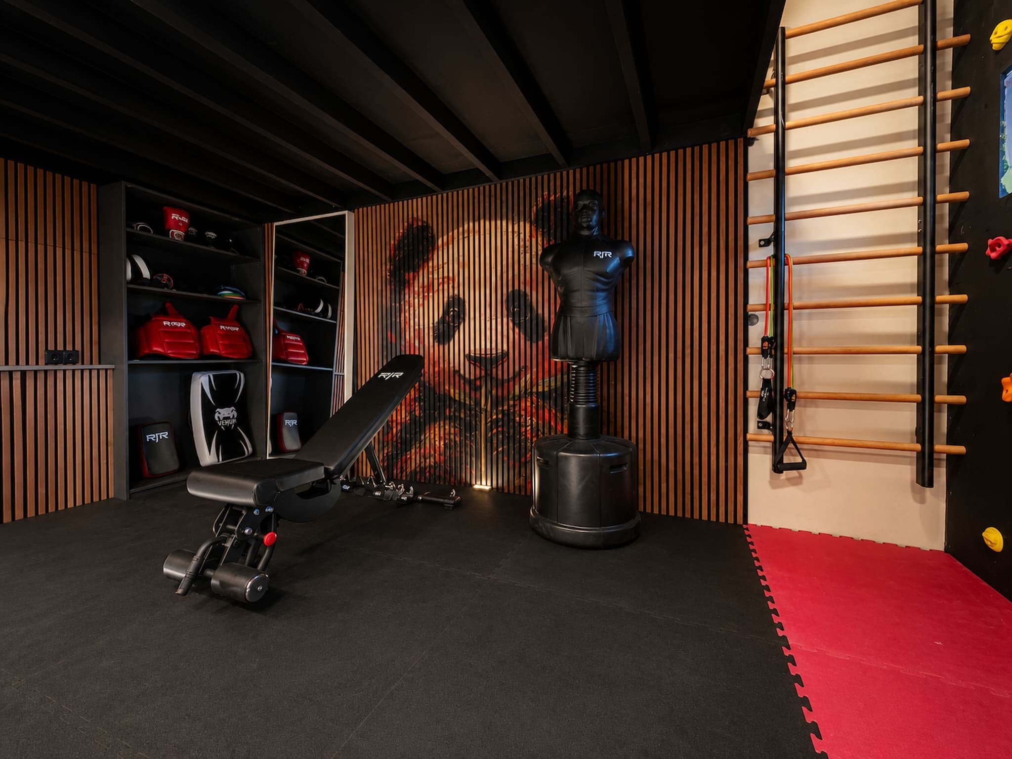Un gimnasio en casa con una prensa de banca, un saco de boxeo y una barra de dominadas fijada a la pared.