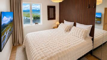 Un dormitorio con una cama grande, una ventana con vistas, un cabecero de madera y un espejo.