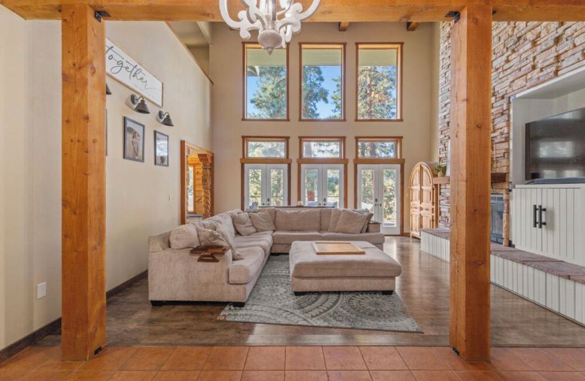 A spacious living room with a large sectional sofa, a fireplace, and a stone wall.