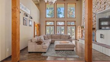 A spacious living room with a large sectional sofa, a fireplace, and a stone wall.