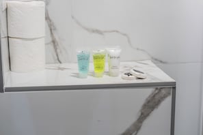 A bathroom counter with three toiletry bottles labeled 'Just for you' and a roll of toilet paper. - Sutherland Apartments - Apt 31 (London)