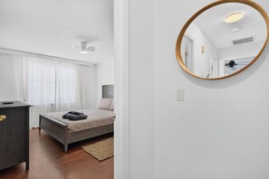Ein Schlafzimmer mit Bett, Schminktisch, Spiegel und Deckenventilator.