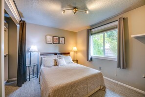A bedroom with a bed, two bedside lamps, a window with curtains, and a ceiling light fixture. - The Warm Timber Retreat (Vancouver)