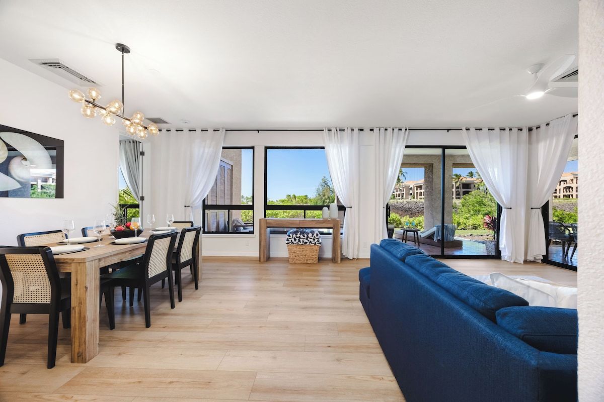 Una sala de estar moderna con comedor, ventanas amplias y vistas al exterior.