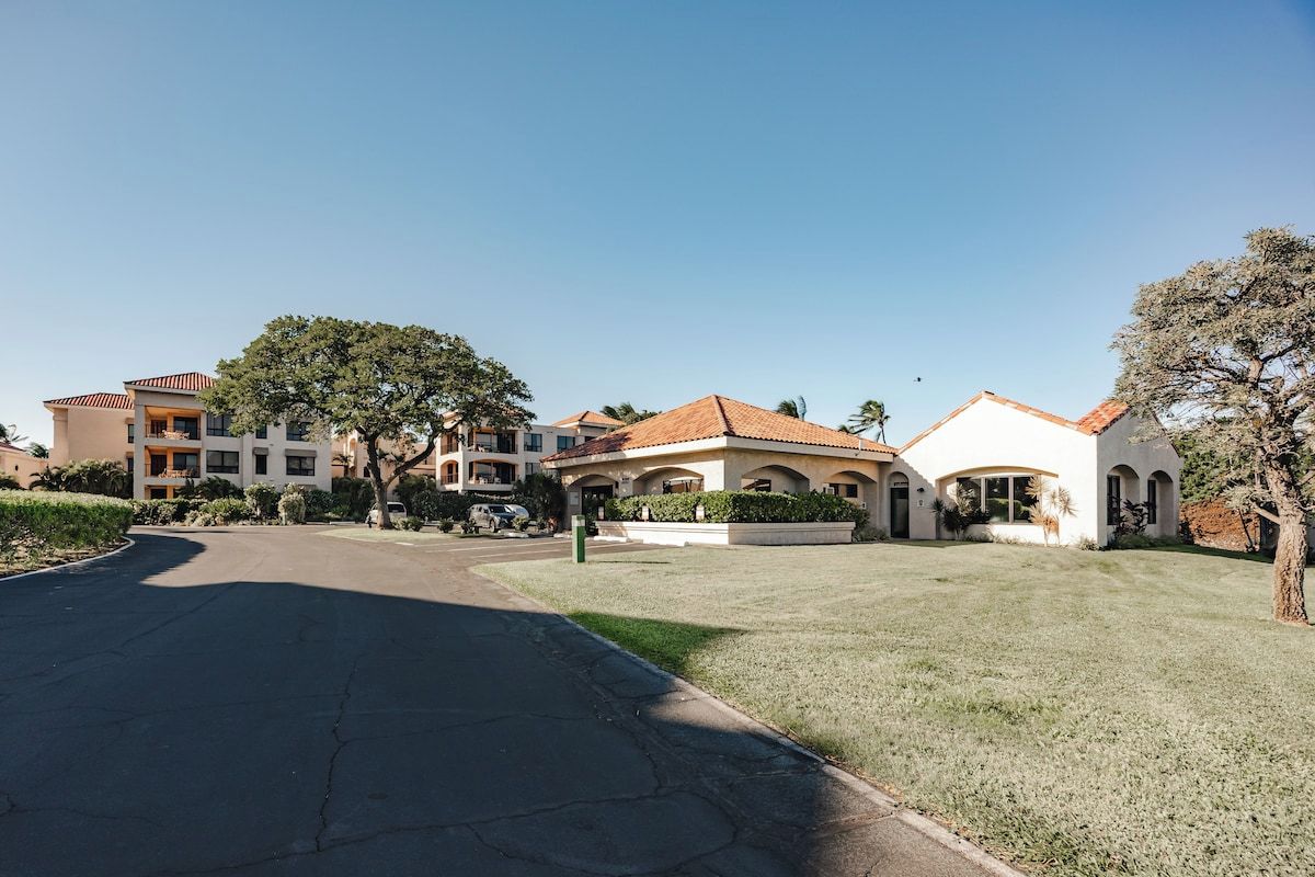 A residential area with multiple houses, a clear sky, and a well-maintained lawn.
