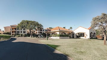 A residential area with multiple houses, a clear sky, and a well-maintained lawn.