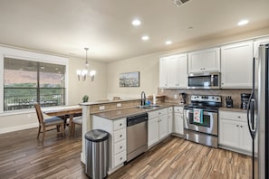 A modern kitchen with white cabinets, stainless steel appliances, and a wooden floor. - Hilltop Lake Views | Hollows Resort Amenities (Jonestown)
