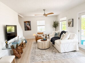 Ein Wohnzimmer mit Flachbildfernseher, Deckenventilator, Sofa, Couchtisch und Teppich.