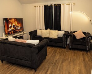 Ein Wohnzimmer mit Kamin, zwei Sofas, einem Couchtisch und einem Fernseher.