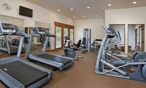 Ein Fitnessstudio mit Laufbändern, Crosstrainern und Gewichtsgeräten.