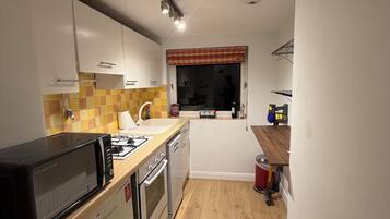 A compact kitchen with white cabinets, a microwave, a stove, and a sink.