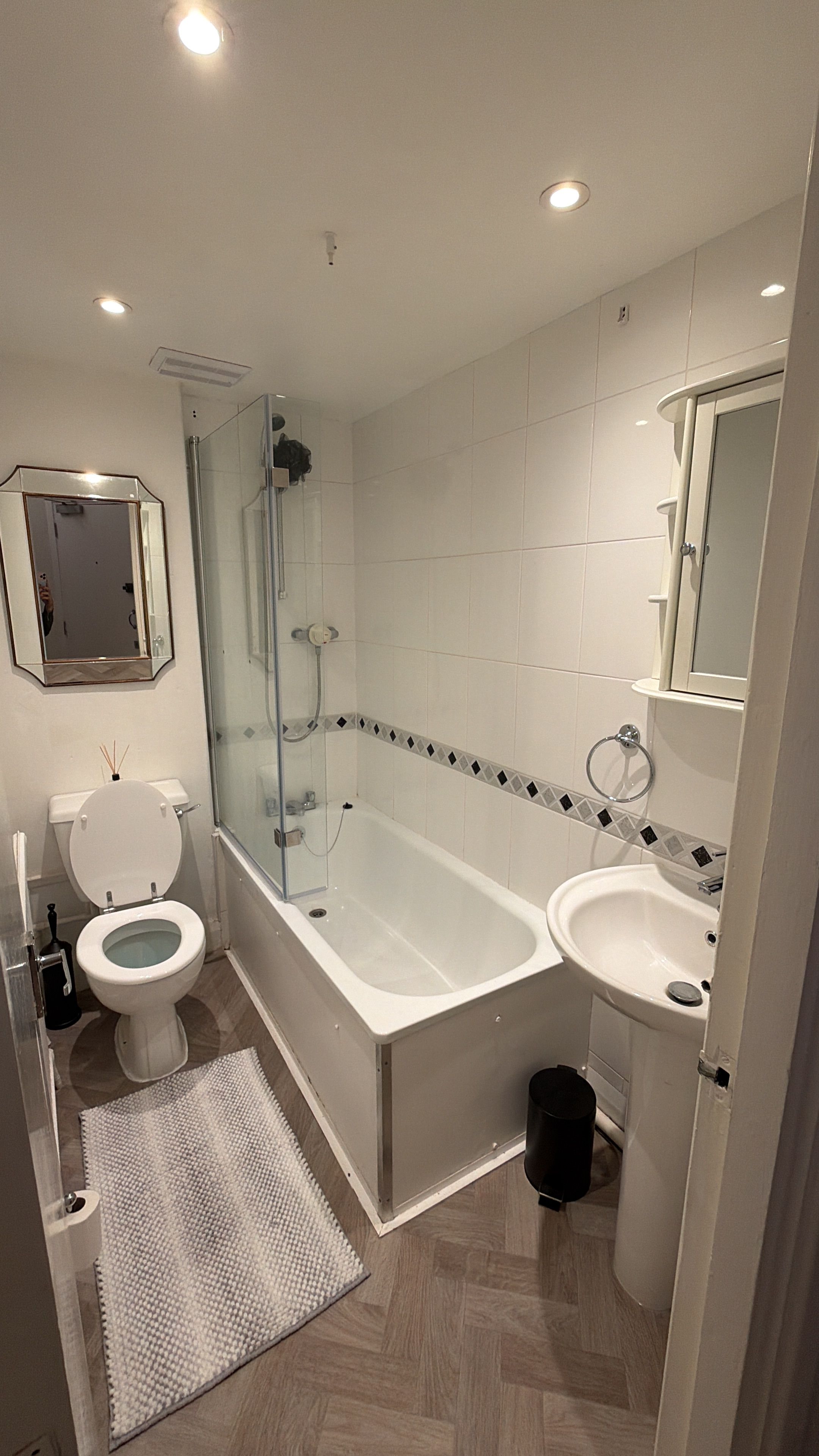 Un baño moderno con ducha envuelta en vidrio, inodoro, bañera y lavamanos.