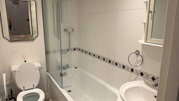 Un baño moderno con ducha envuelta en vidrio, inodoro, bañera y lavamanos.